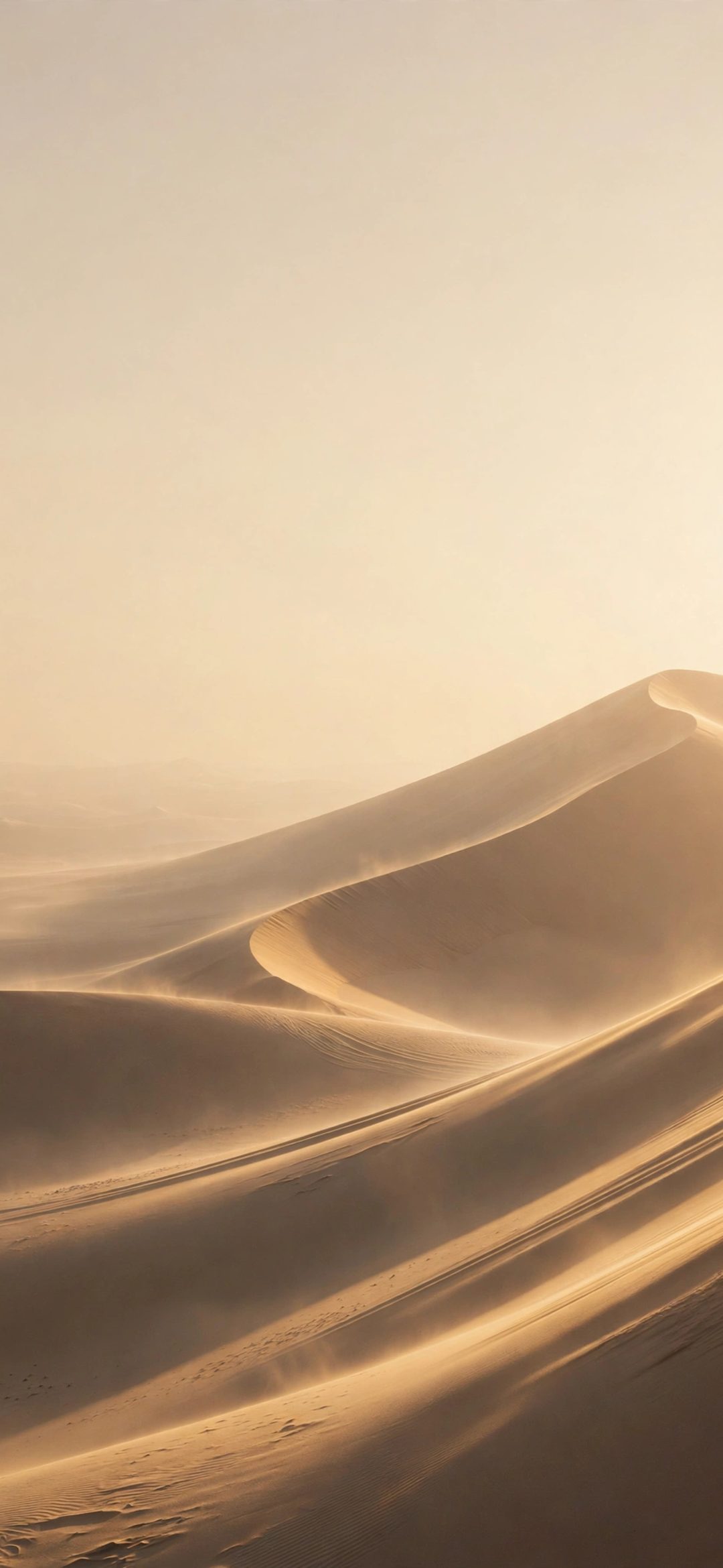 Golden sand dunes under a hazy pale sky with wind-blown sand