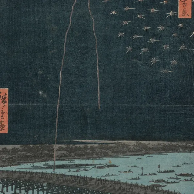 Fireworks bursting over a dark river and bridge at night