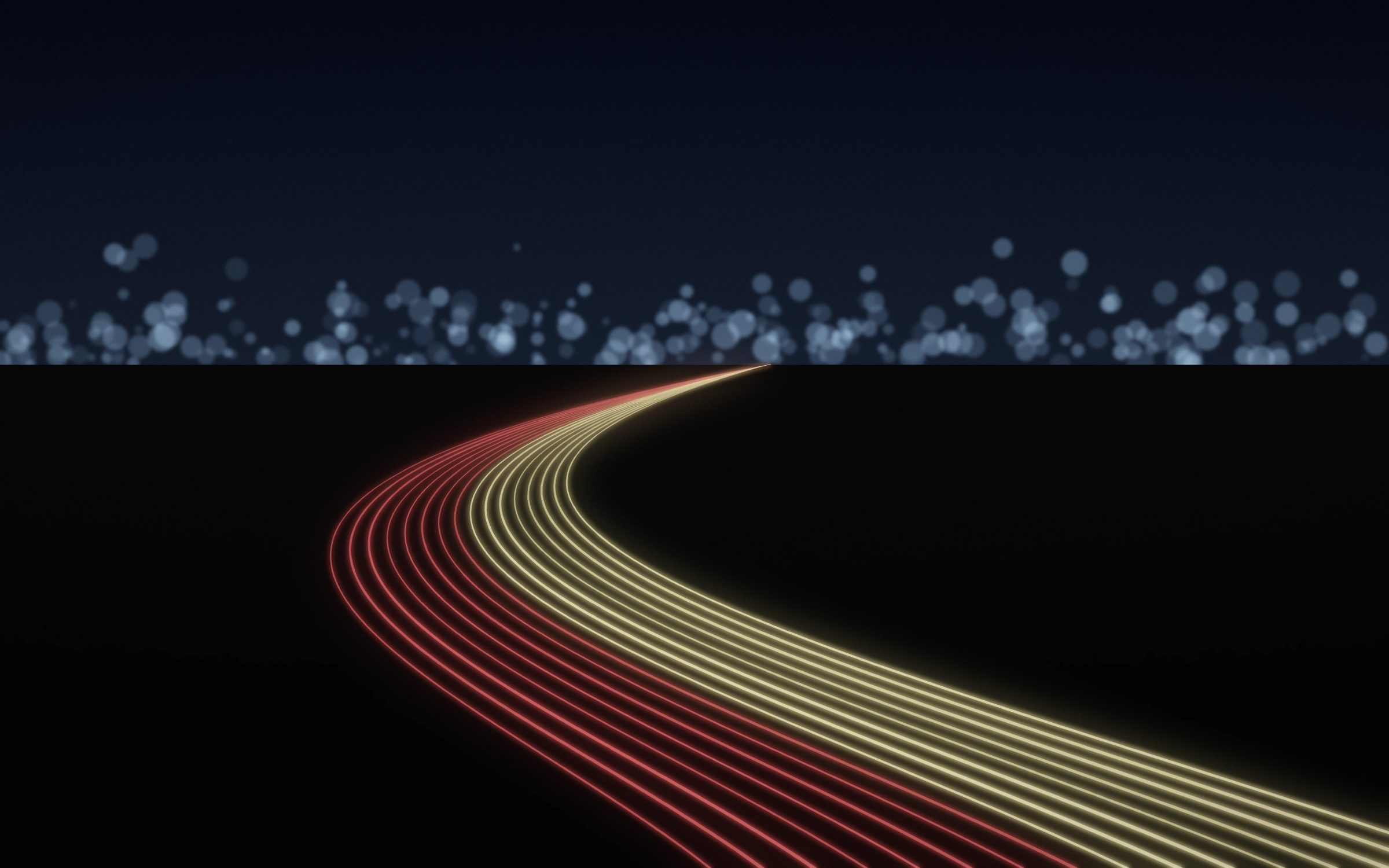 Freeway Light Ribbons: long streaks of red and gold light sweep across a dark freeway curve, the horizon lit by soft, blurred city lights, Mac wallpaper