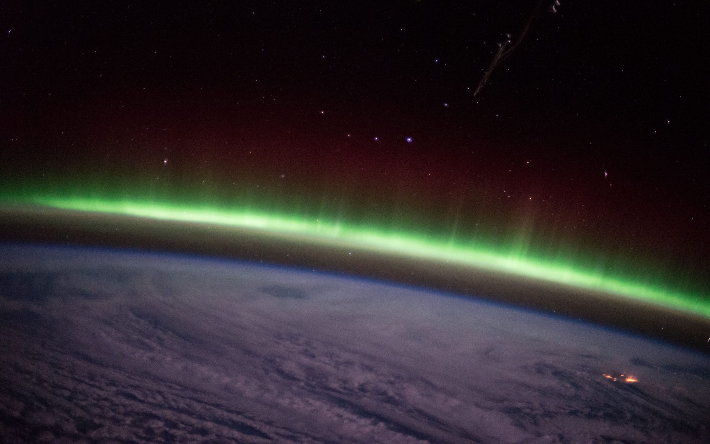 Thin green aurora along the horizon of Earth at night from space