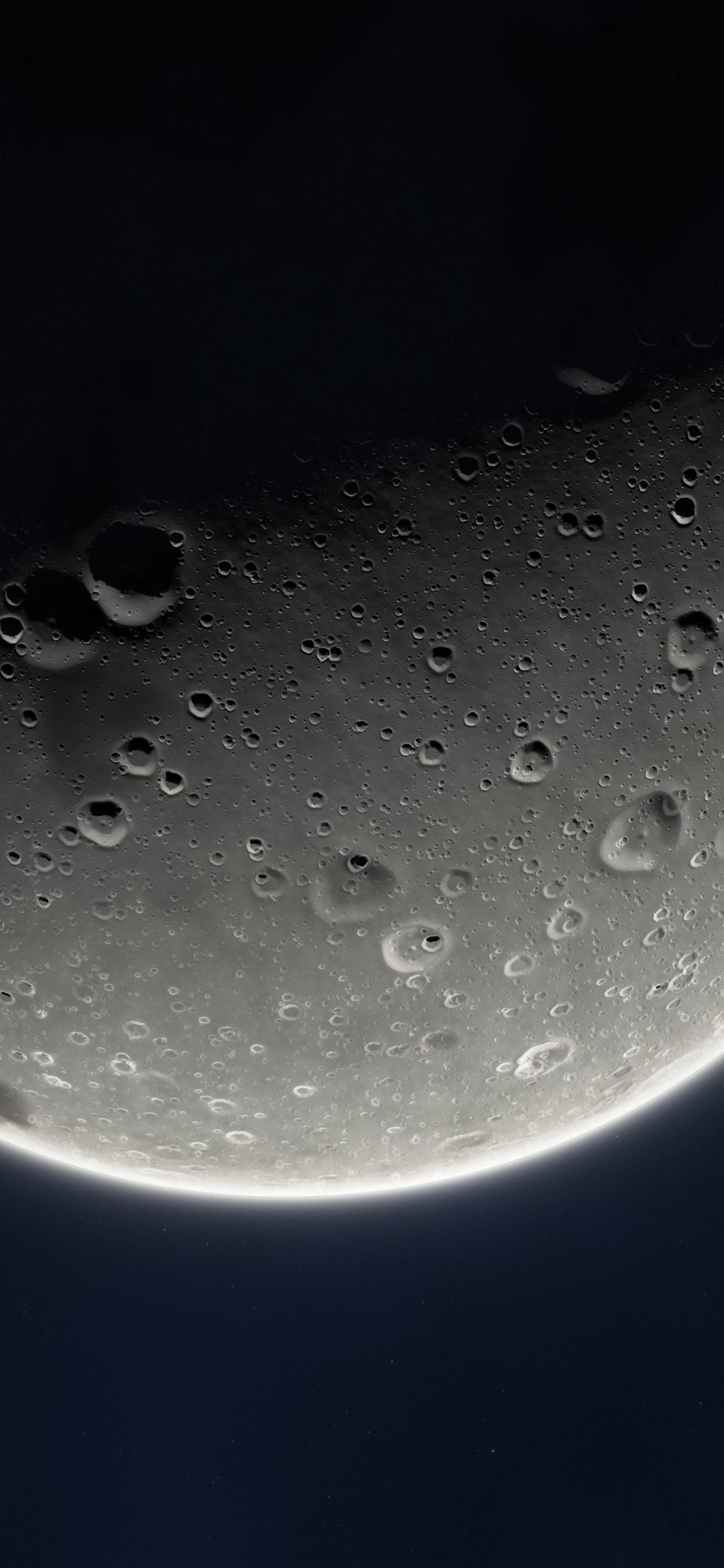 Huge Moon Rim Glow: a huge cratered moon fills the screen at an angle, lit from below so a thin bright rim glows against the dark sky, iPhone wallpaper