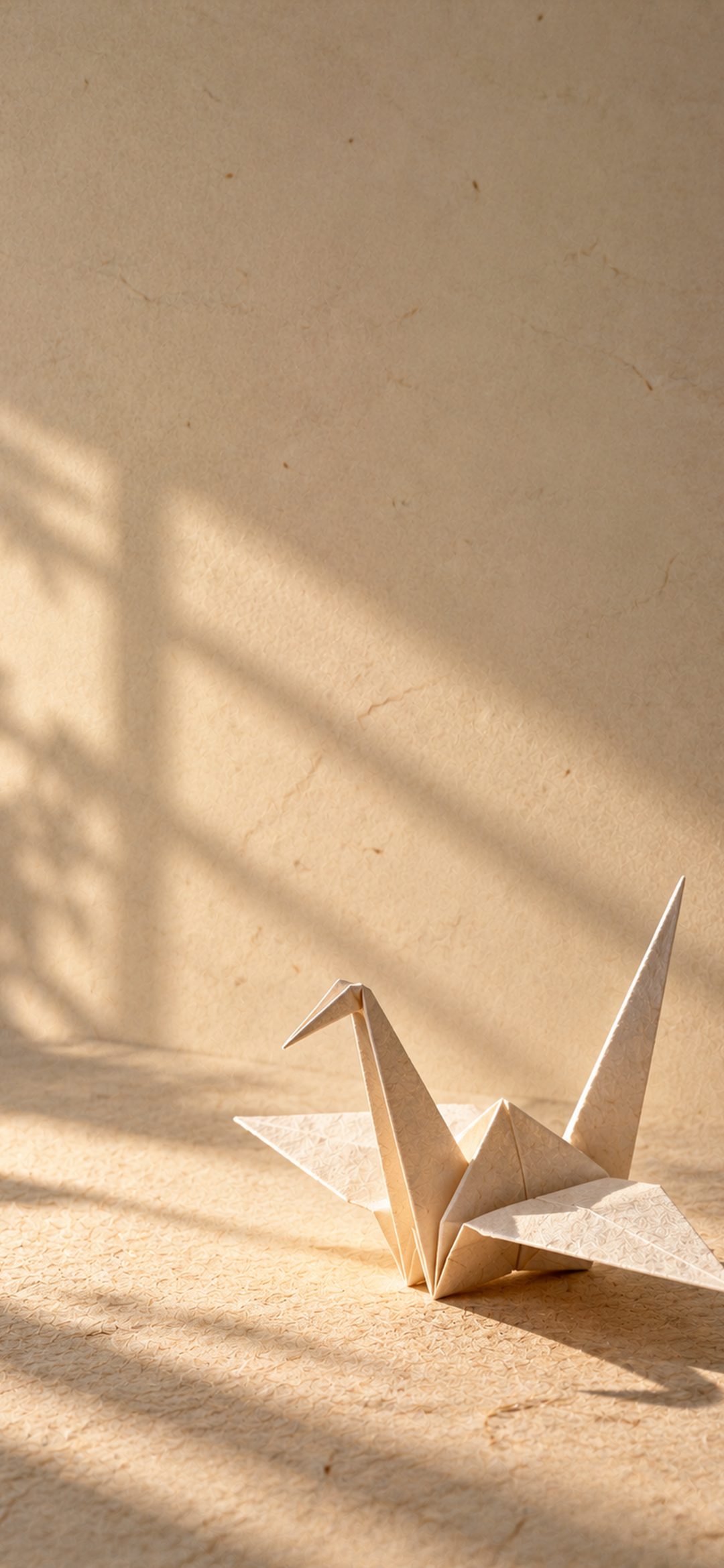 Cream-colored origami crane resting on textured beige paper with soft natural shadows