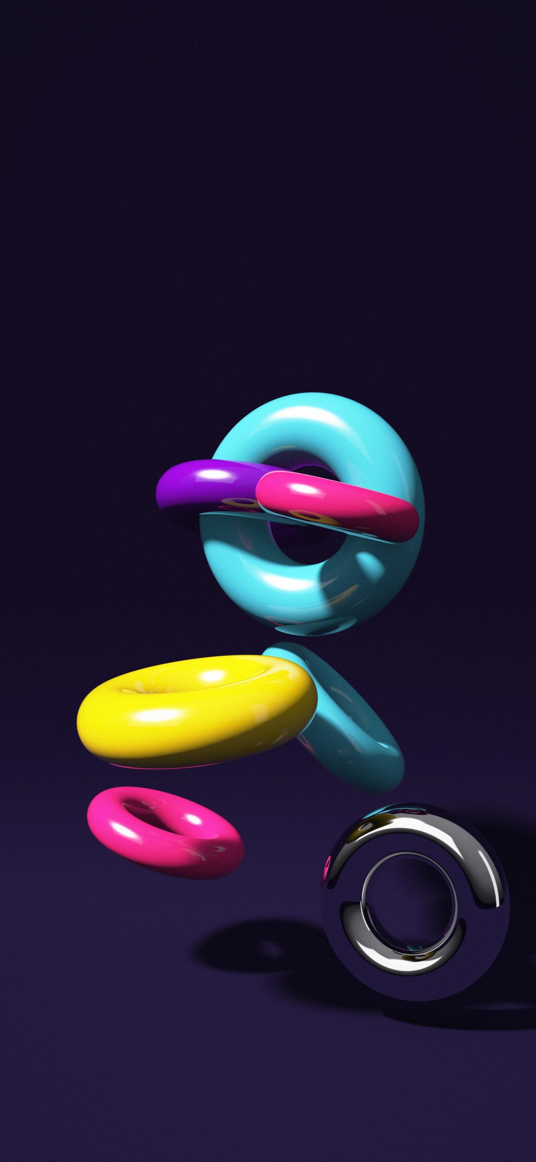 Neon Tori Scatter: magenta, cyan, yellow and purple glossy tori float at odd angles with one gold ring over a dark indigo studio floor, iPhone wallpaper