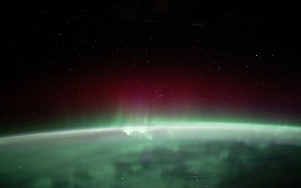 Green and red aurora over the night side of Earth seen from orbit