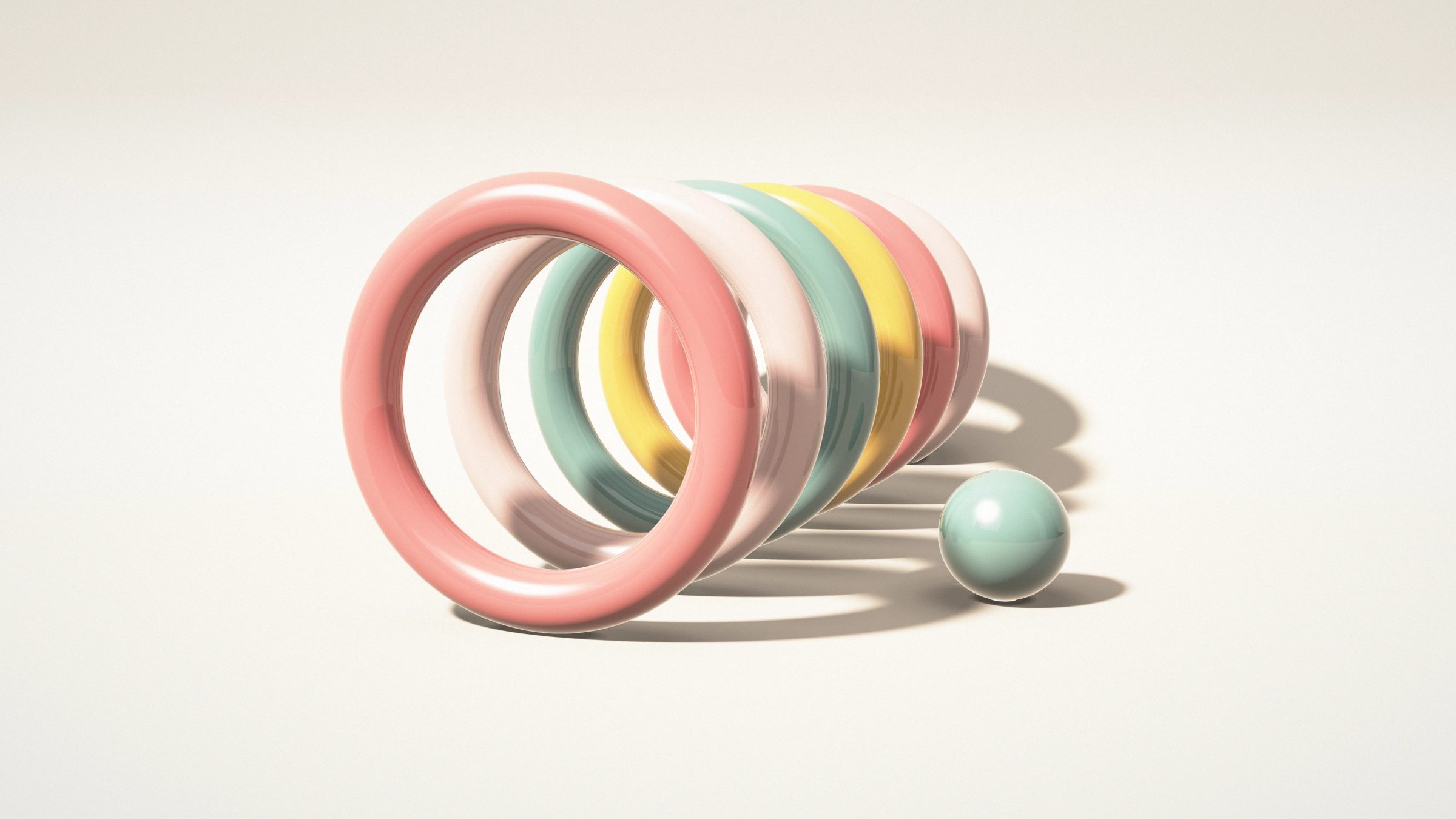 Pastel Hoop Parade: a row of standing hoops in coral, blush, sage and butter yellow recedes across a cream studio floor next to a small ball, PC wallpaper