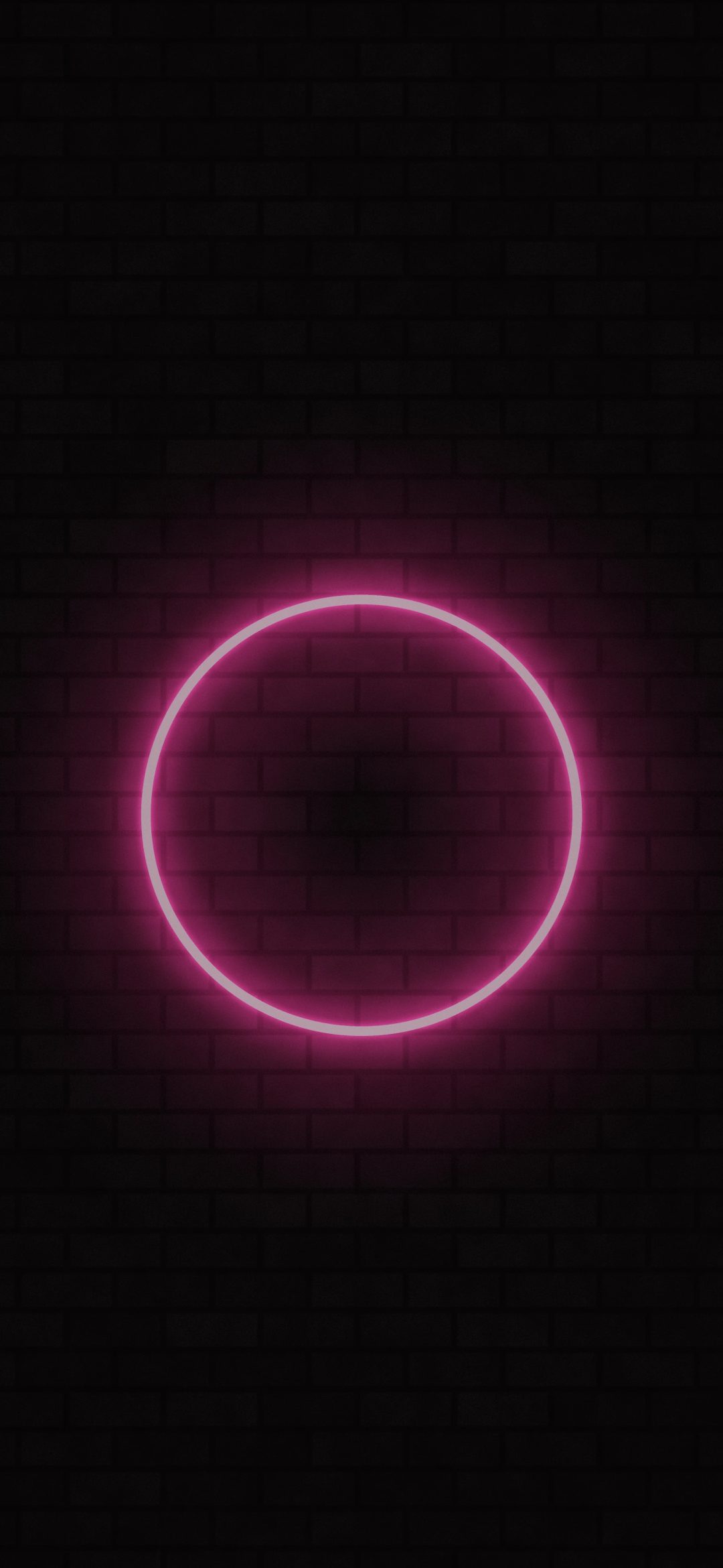 Pink Neon Halo: a glowing pink neon ring hangs on a dark brick wall, its light spilling across the bricks in a warm magenta haze, iPhone wallpaper