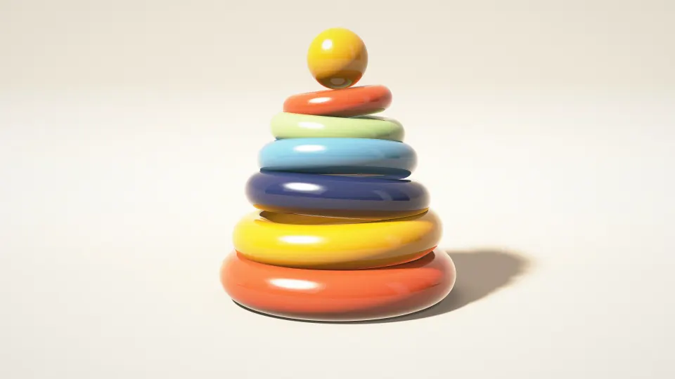 Rainbow Ring Tower: six glossy rings in orange, yellow, navy, sky blue and green stack into a toy tower topped by a ball on a cream floor, PC wallpaper