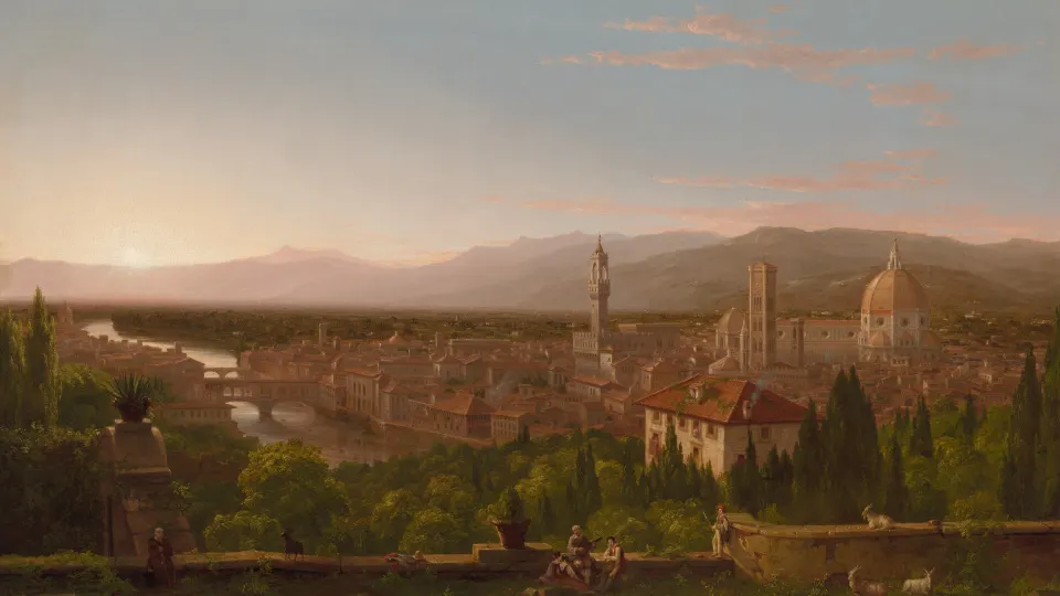 City with domes and towers in a wide valley at golden hour, hills behind