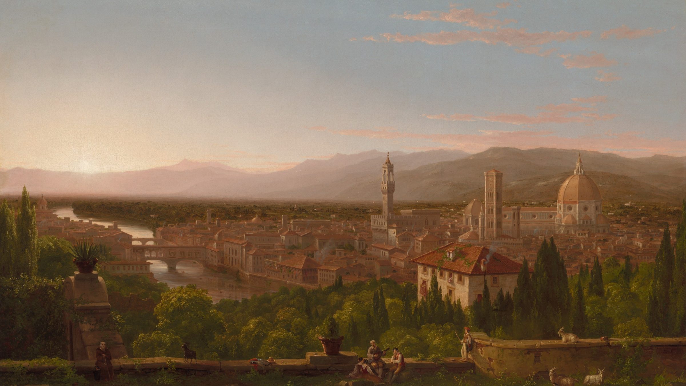 City with domes and towers in a wide valley at golden hour, hills behind