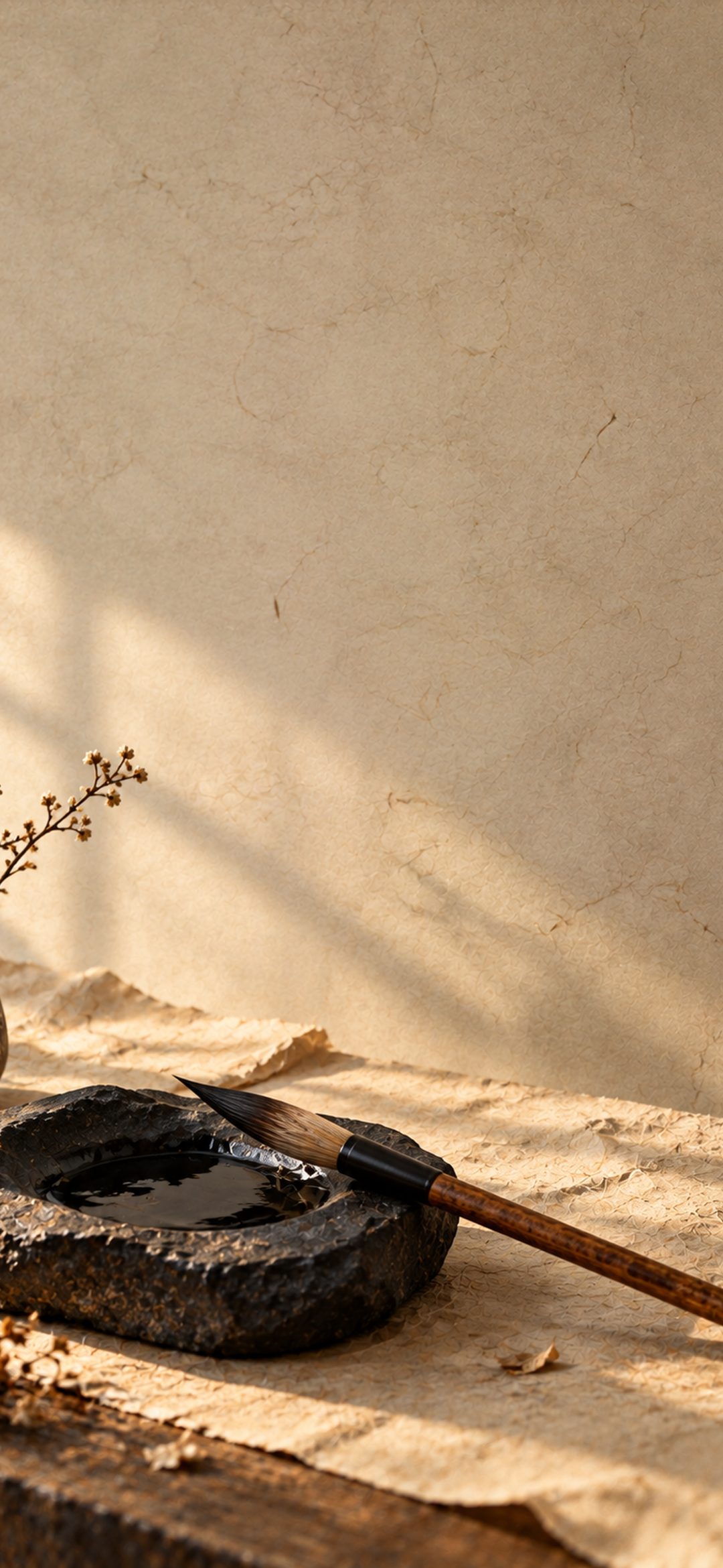 Traditional wooden calligraphy brush resting beside a dark stone inkstone filled with black ink on aged beige paper.
