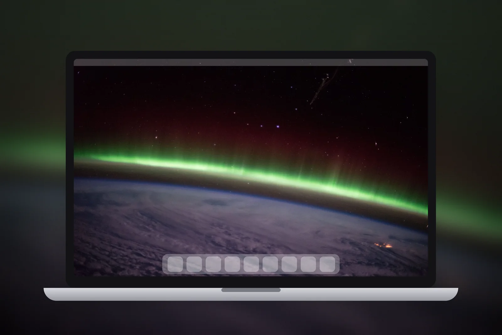 A Mac laptop showing the Green Aurora Arc wallpaper on its desktop